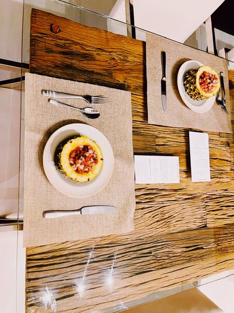 A table set for two with an appetizer at each place, on a live-edge wood table